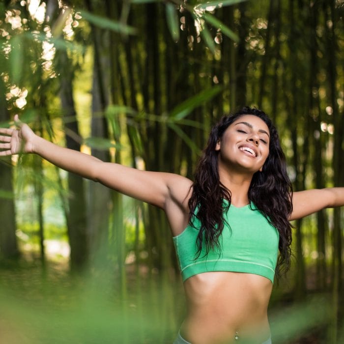 Woman stretching her arms in bamboo garden